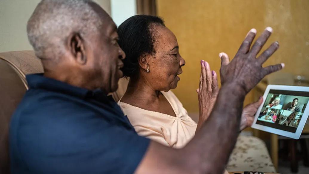 grandparents calling on an ipad for a video call with family waving hi