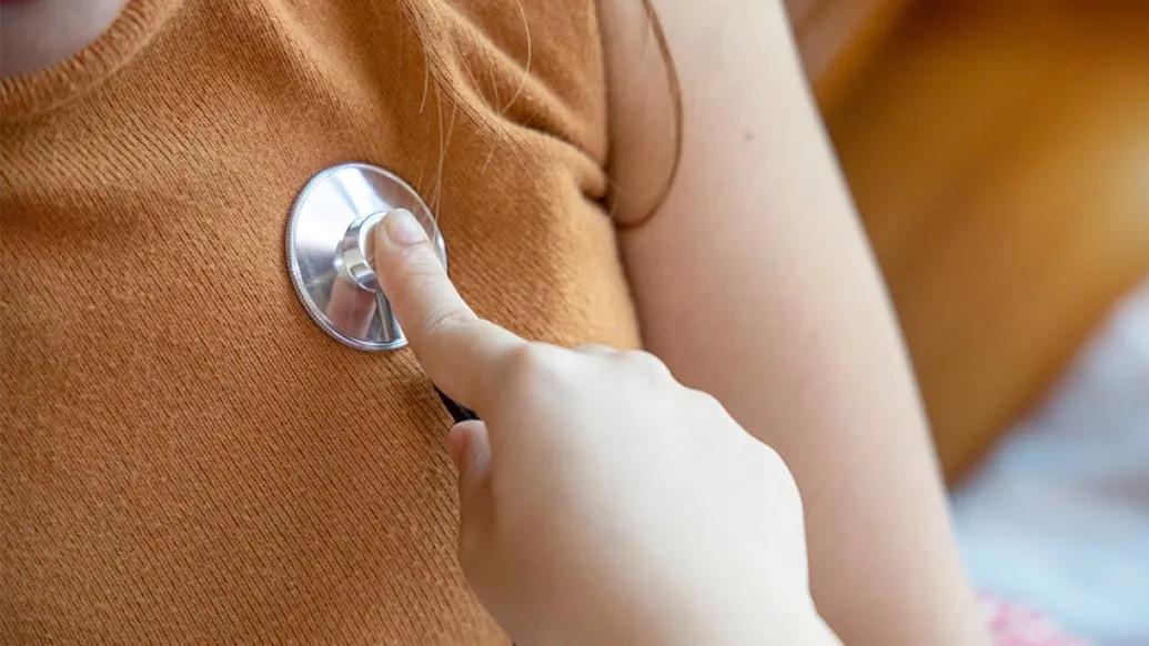 stethoscope on heart of orange shirt close up