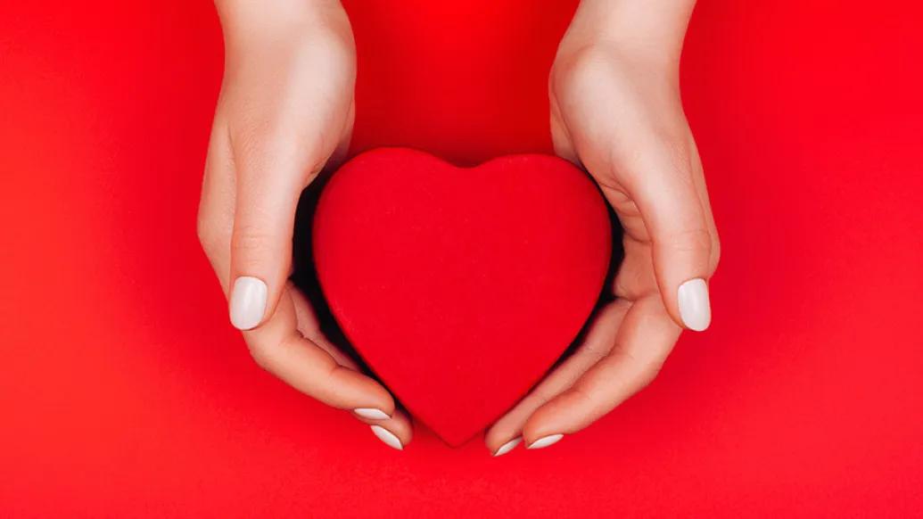 red heart held in hands in heart background