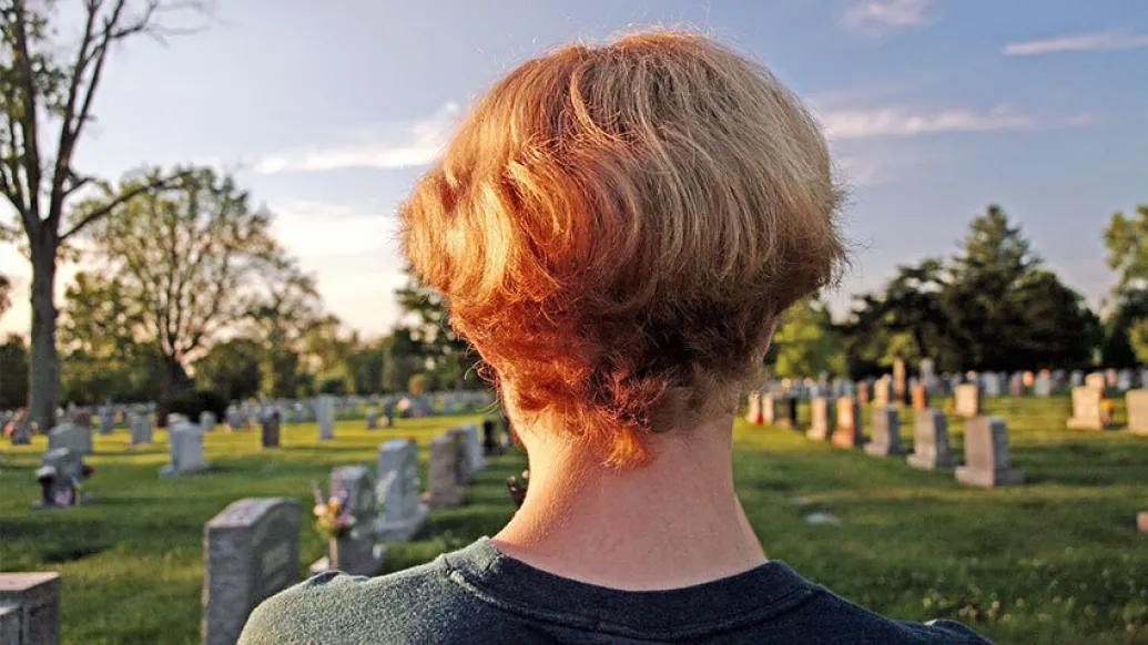 head shoulders view from back in front of graveyard headstones with sun and blue sky