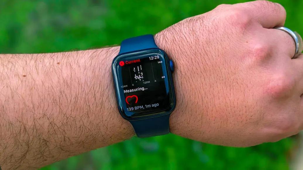 man's arm with eye watch over green field 