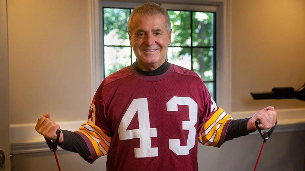 Man in red football jersey exercising with bands and smiling in room