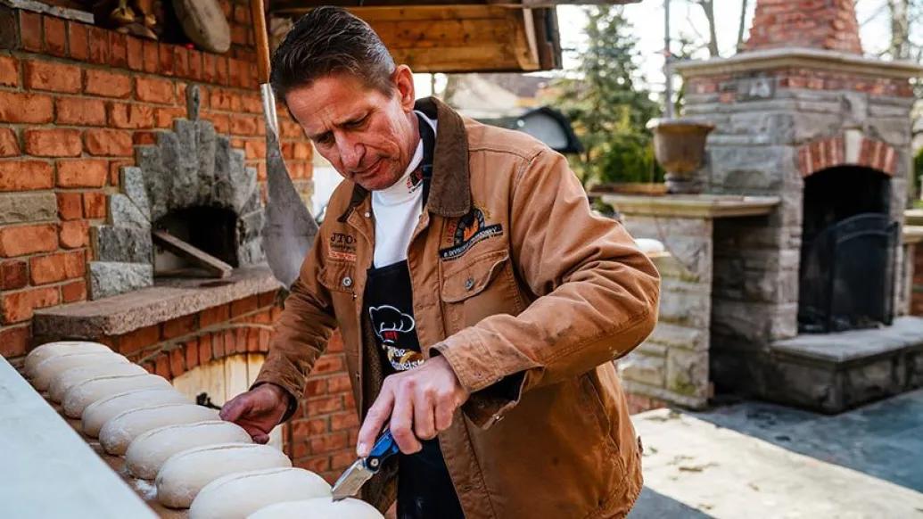 man slicing dough knife bread
