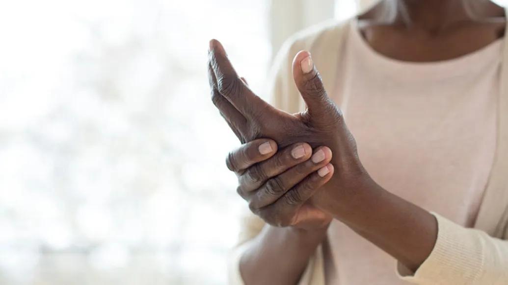Woman in white shirt by window rubbing her hands