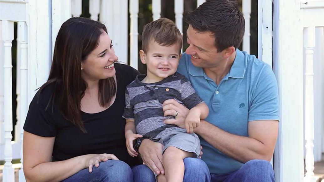 Mother and father sitting on porch with son smiling