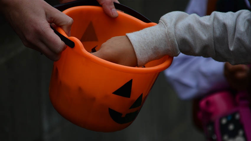 Orange pumpkin bag of candy with kids reaching inside