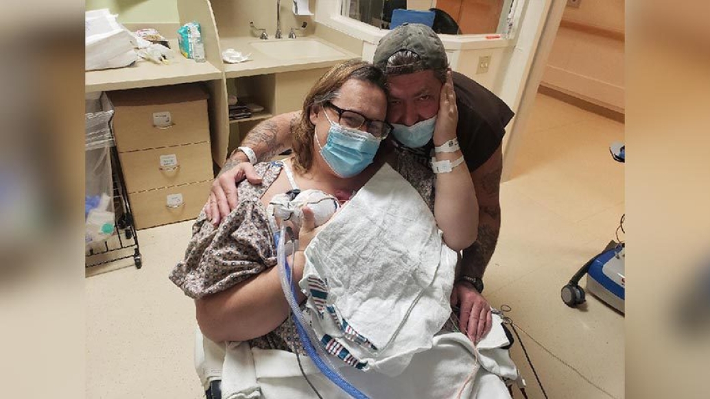 parents holding baby in hospital wheelchair