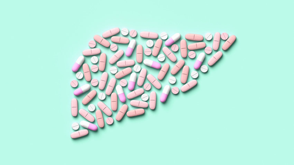 Pills medicine shaped of liver organ on teal background