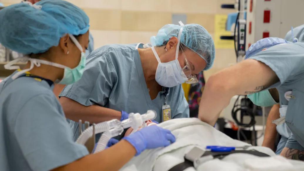 three surgeons in scrubs and masks intubating patient tub