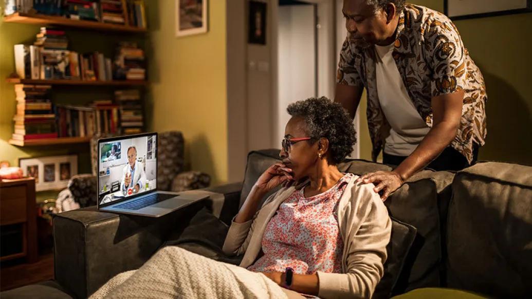 senior couple on couch with doctor on laptop