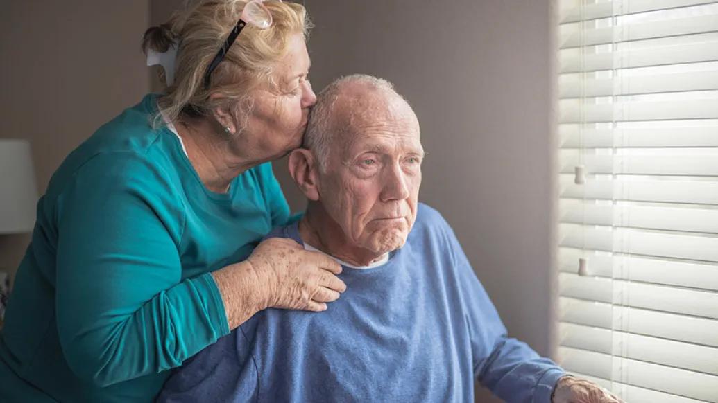 senior couple kiss forehead window