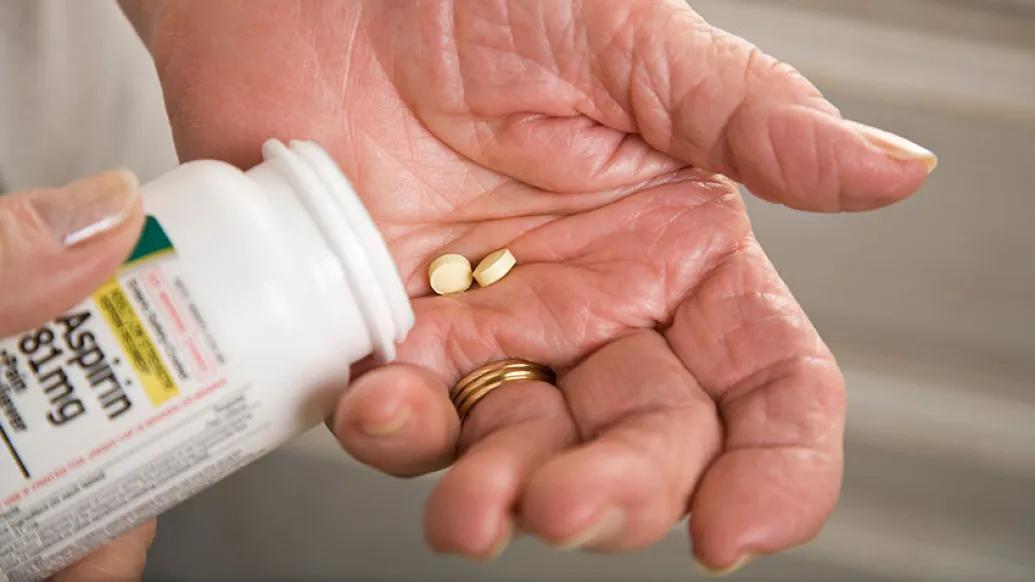 Hand pouring aspirin pills into hand