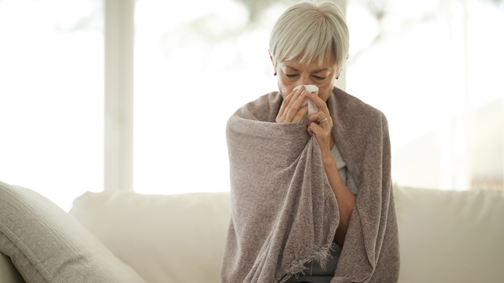 senior woman blowing nose blanket