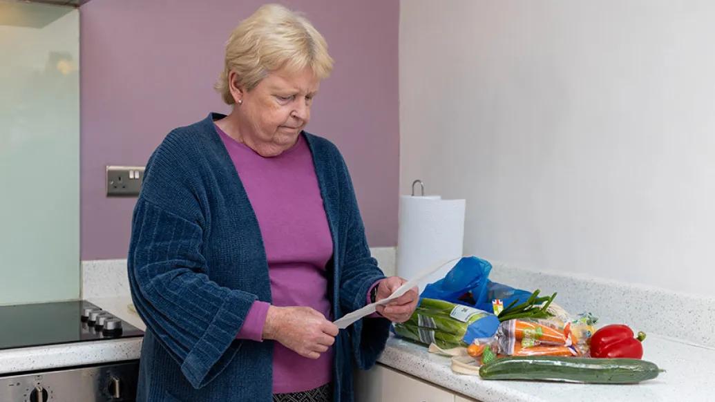 senior woman looking at receipt of groceries