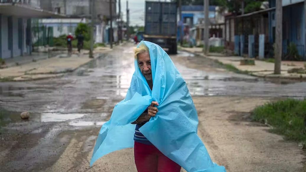 older woman with tarp over here in rain hurricane