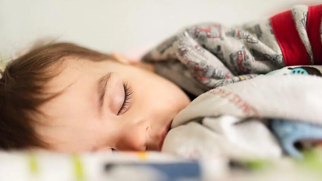 Sleeping child laying in bed with blankets