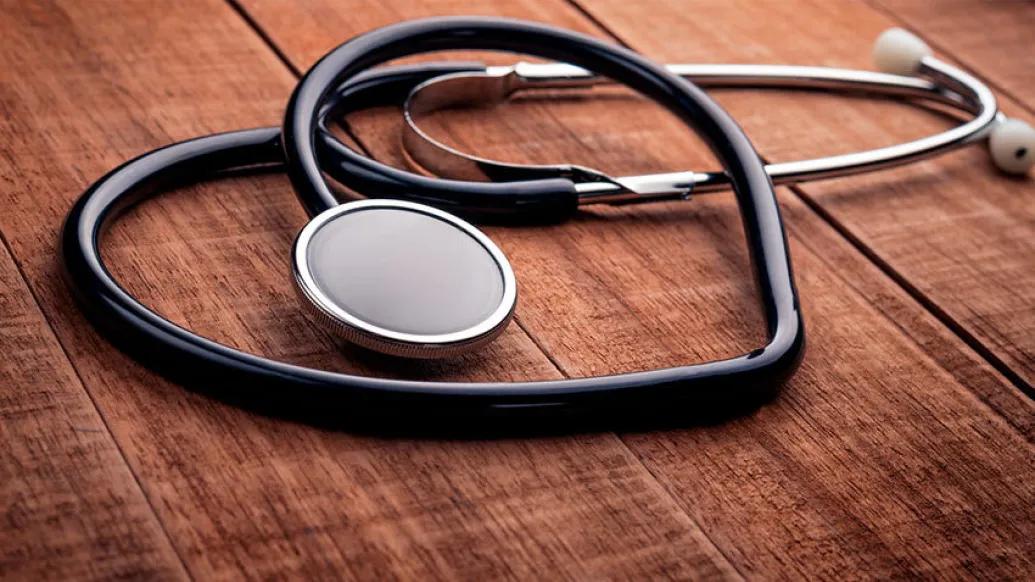 stethoscope in heart shape on wooden table