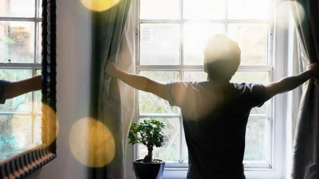 Child opening curtain and sun shining through
