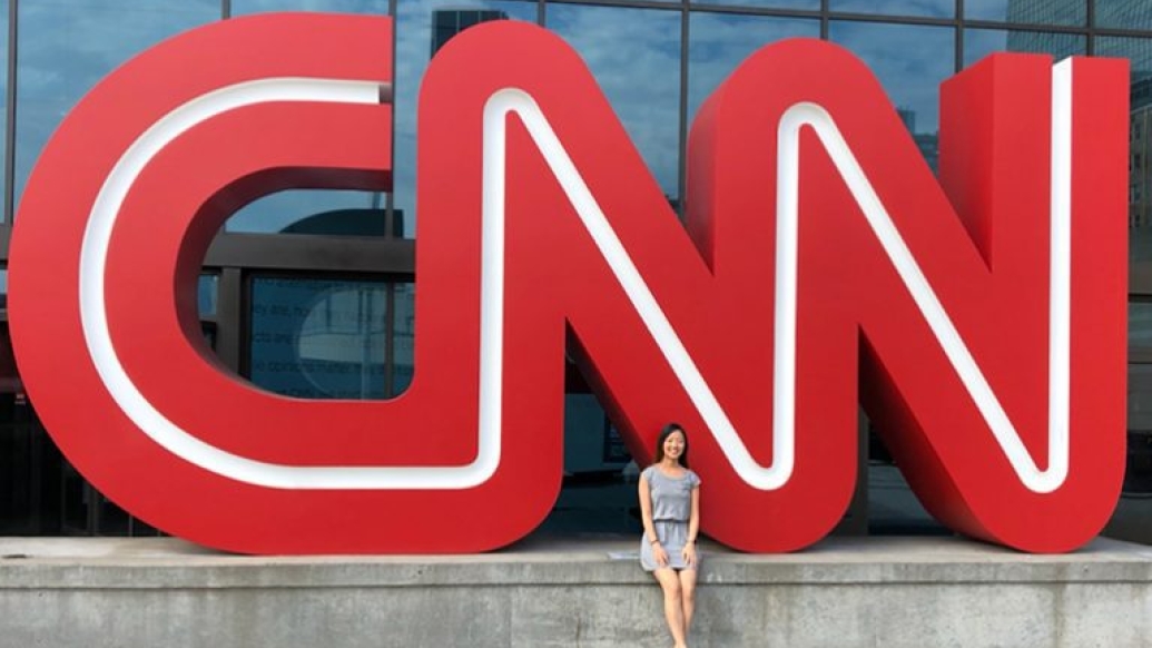 student in front of red CNN sign 