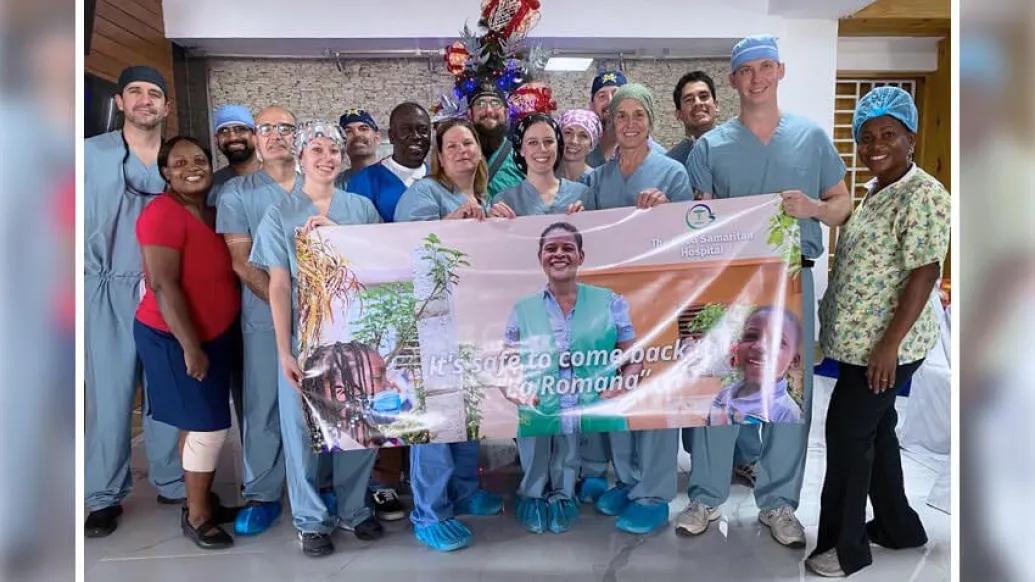 Surgery staff holding banner in hospital smiling wearing blue scrubs, It's safe to come back La Romana