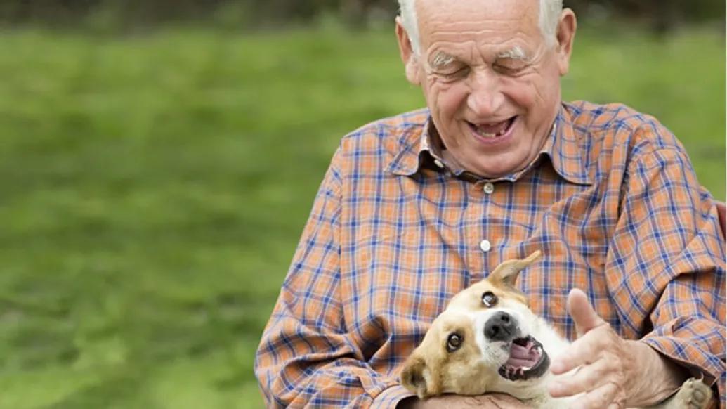Older man rubbing a dog's neck