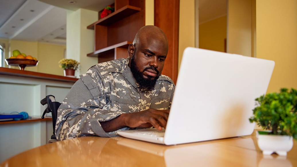 veteran in wheelchair on laptop in kitchen