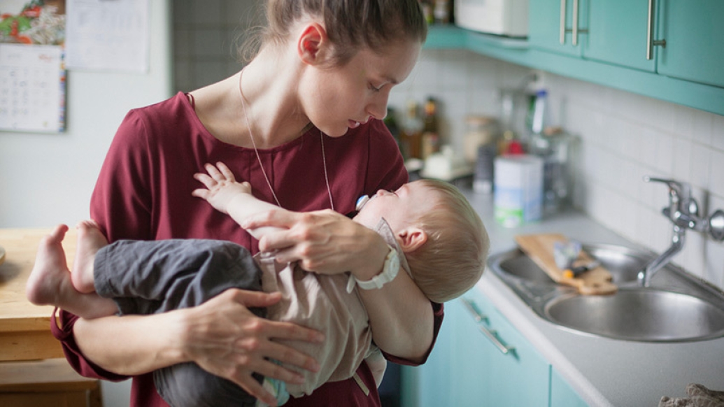 woman holding sleeping baby kitchen