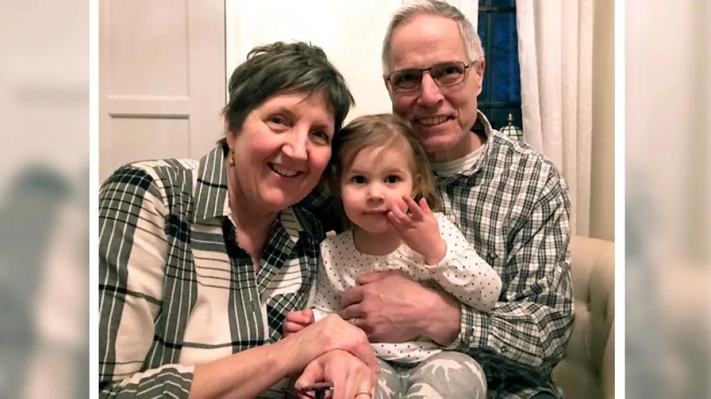 Woman and man wearing plaid smiling while holding child