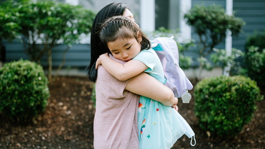 young girl hugging her mother backpack