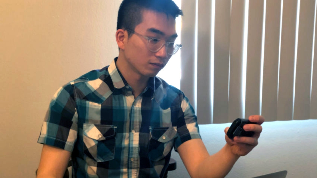 Young man in plaid shirt looking at pager