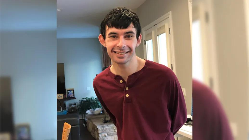 young man in red shirt smiling standing in kitchen