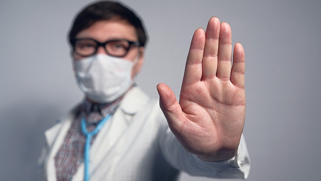doctor holding hand up in mask with glasses and mask