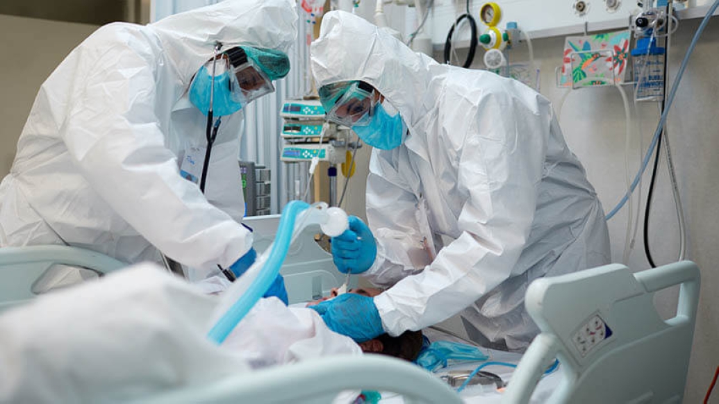 Doctors inserting ventilator tube hazmat suits
