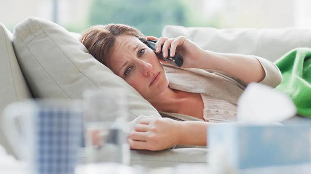 woman sick on couch on phone