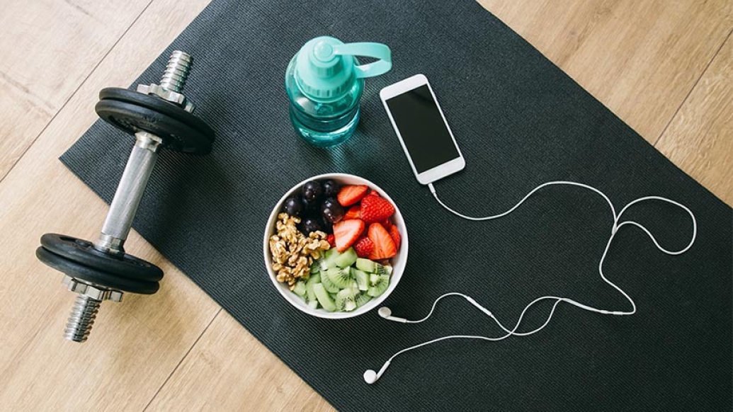 image of weight phone headphones bowl of fruit and water bottle.