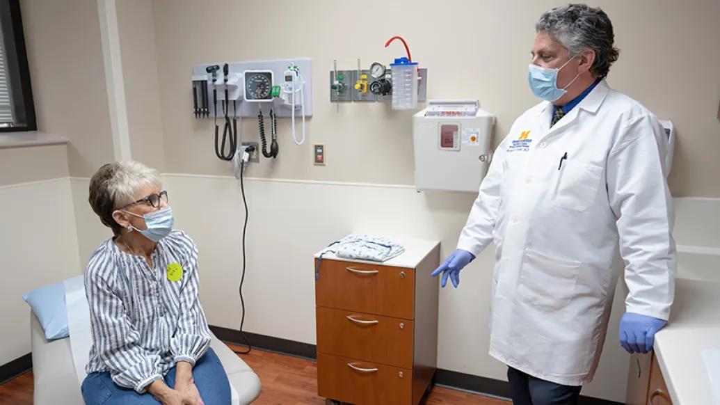 patient with mask on looking at doctor in exam room with mask on standing