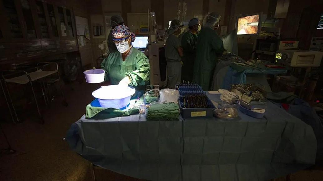 surgeon in dark operating room with light shone on them