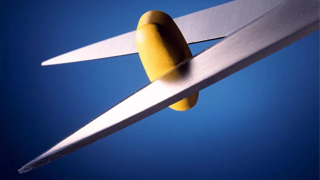 Scissors cutting a pill in half