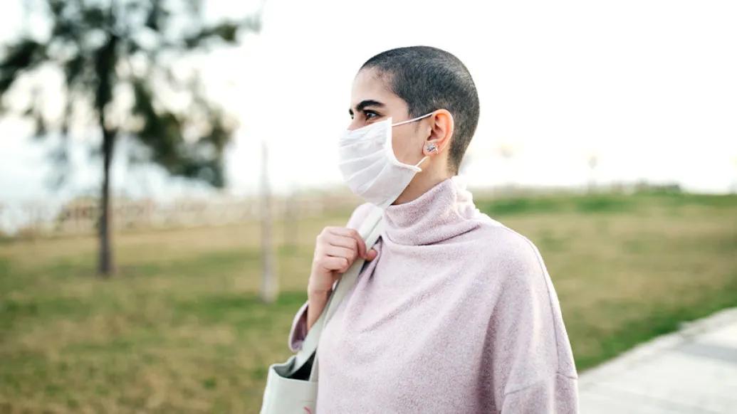 woman standing mask in pink shirt outside
