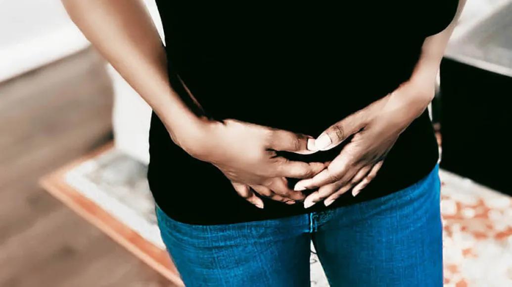 Women holding hands on lower front torso with pain