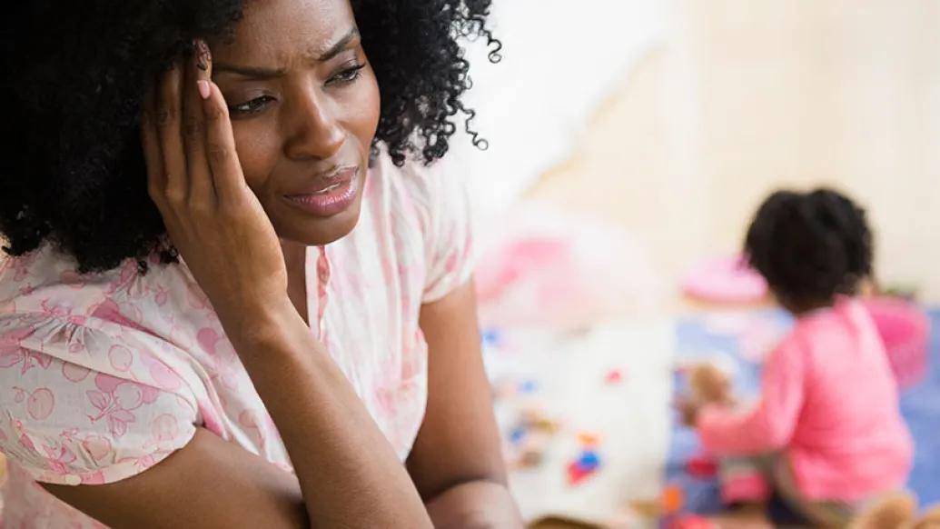 young mother holding head with child in background