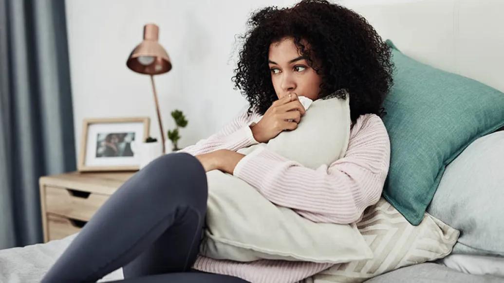 young woman lying down on bed hugging pillow