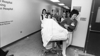 1986 photo of staff moving a patient in the new hospital