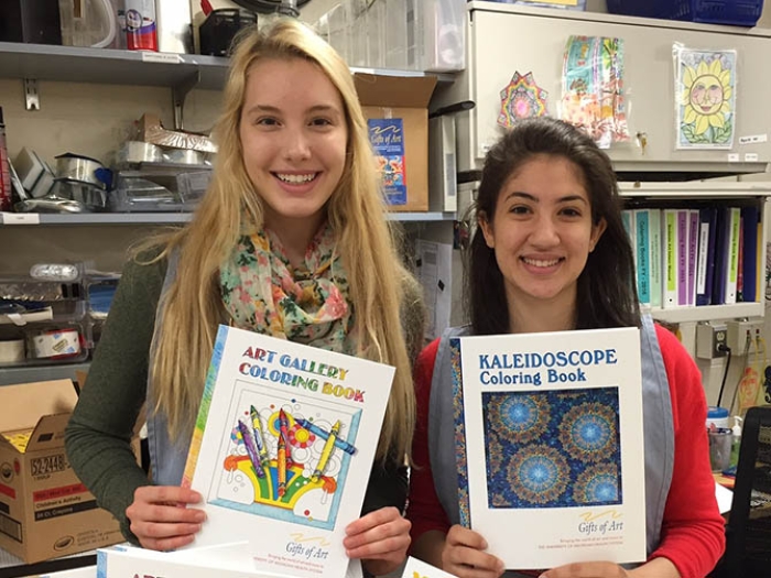 Two teen girls displaying coloring books