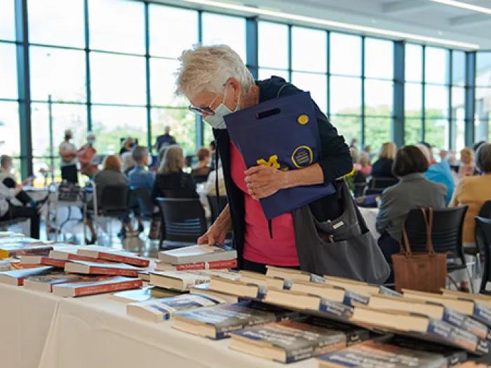 Elderly woman looking at books and magazines lying on table