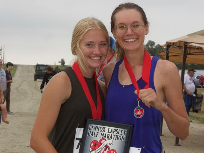 two girls wearing red ribbon medals and holding a plaque