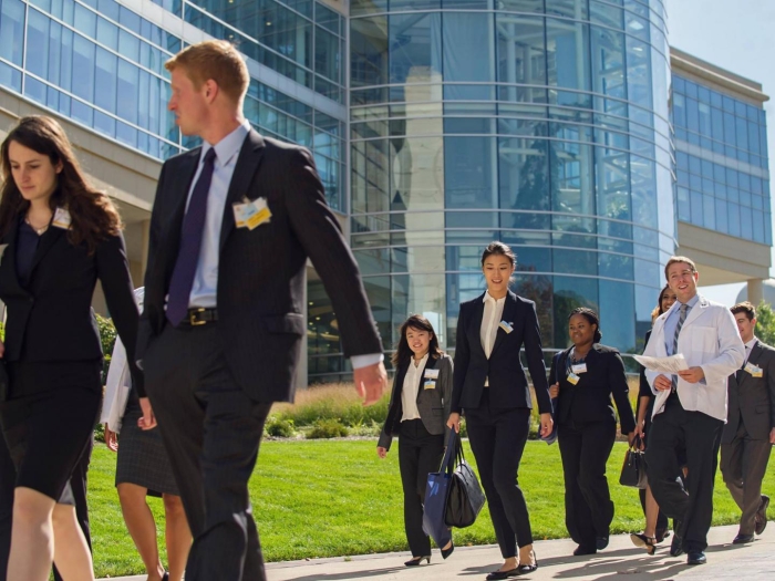Young men and women wearing dark suits walking in front of U-M Frankel Cardiovascular Center