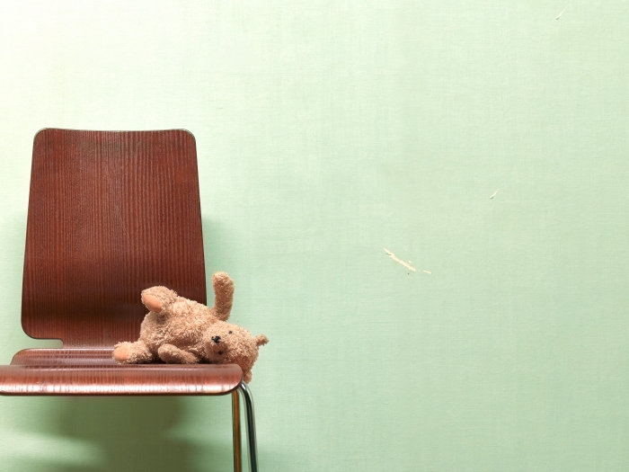 Empty chair with a teddy bear laying on it.