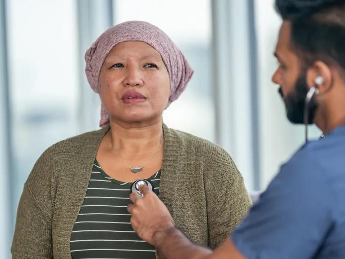 Woman with a headscarf having her heart checked by a man with a stethoscope.