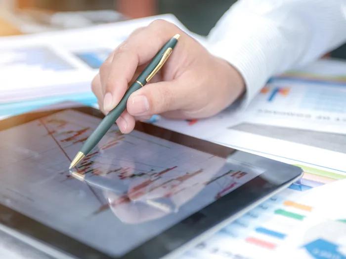 Hand holding pen on tablet.